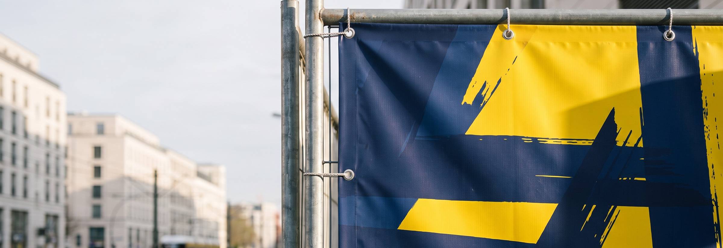 Bedrucktes PVC-Werbebanner mit Ösen am Bauzaun in Berlin